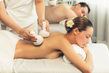 Sıcak bitkisel top spa masaj vücut tedavisi, masör nazikçe bitki torbasını çift müşteri vücuduna bastırıyor. Aromaterapi dinlenme sükuneti ve sükuneti kaplıca salonundaki atmosferi aydınlatıyor. Sessiz.