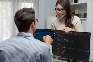 Masada çalışan erkek programcının karşısında duran kadın meslektaşım iki bilgisayar ekranında kodlama web sitesi yazılım sistemi projesini tartışmak için tam yığın veri dizaynı ile karşılaştırıyor. Varsayım.
