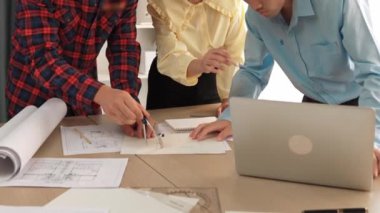 Mimarlık ve güvenlik mühendisi, modern ofiste doğruluk için mimari belge ve ölçüm aracı kullanılarak dizüstü bilgisayarın üzerinde sergilenen planlar hakkında tartıştı. - Yakın çekim. Tanımlama.