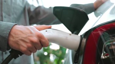Yavaş çekim çift yazın yeşil sürdürülebilir şehir açık bahçesinde elektrikli araba şarj ile seyahat elektrikli aracın temiz yeniden şarj edilebilir enerjisi için kentsel sürdürülebilirlik yaşam tarzı olarak