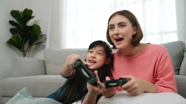 Kafkas anne ve kızı oturma odasında oturup oyun oynuyorlar. Mutlu anne, elinde joystick tutarken akıllı Asyalı kızla vakit geçiriyor. Oyun oynamaktan zevk alıyor. Yaşam tarzı konsepti. Pedagoji.