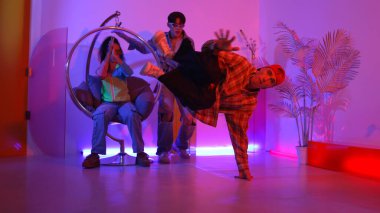 Stüdyoda gündelik kıyafetleri olan çok kültürlü bir arkadaş tezahürat yaparken mutlu hipster break dansları. Profesyonel sokak dansçısı hip hop ritmi ya da neon veya kurşun ışıkla kafiyeli bir şarkı söyler. Mutluluk.