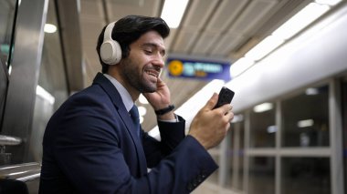 Tren istasyonunda geçmişi bulanık bir şekilde beklerken kulaklıkla müzik dinleyen zeki bir iş adamı. Yetenekli proje yöneticisi cep telefonu tutarken dinlenme sesi dinlemeyi sever. Sevinçli..