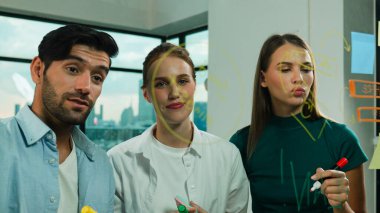 Profesyonel iş adamları beyin fırtınası yapıyor, fikir paylaşıyor, düşünüyor yetenekli erkek liderler cam duvarda yapışkan notlar yazarken. Yetenekli yönetici ofisteki cam duvara iş planı koymuş. İzleme