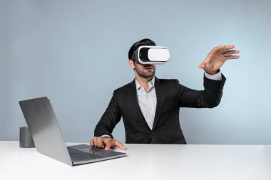 Bilgisayarla masada otururken ve VR gözlüğü takarken veri analizine bakan yetenekli bir iş adamı. Proje yöneticisi sanal gerçeklik sistemini kullanarak ya da metaevrende bağlantı kurarak çalışıyor. Sapma.