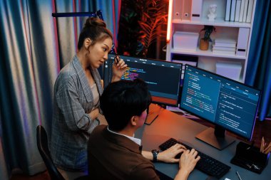 Bilgi teknolojisi modern ofisteki neon ışık odasında iki ekranın bilgisayarında veri çalıştıran akıllı web sitesi geliştirme kodlayıcı sistemi ile tartışan bilişim geliştiricileri. İnfobahn.