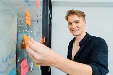 Kafkasyalı profesyonel iş adamının zihin haritası ve renkli yapışkan notlar kullanarak iş pazarlama fikrini kendine güvenle sunuşunun yakın görüntüsü. Proje konseptini başlat. Portre. Tertemiz..