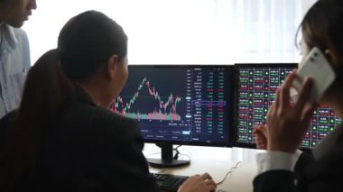 Menkul kıymetler borsası pazarlamasını inceleyen borsa yatırımcıları, zarar ve kazanç için mum bar fiyatlarını analiz eden monitörlere bakıyor. Filizlenen