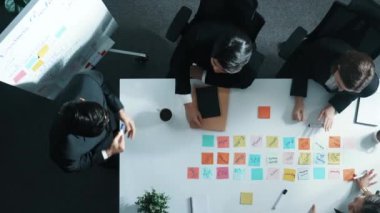 İş adamlarının yukarıdan aşağıya hava görüntüsü proje yöneticisine satışları bildirirken, başlangıç ekibi toplantı odasında artan karı kutlamak için el çırpıyor. Bir grup yönetici bir çözüm buluyor. Müdürlük.