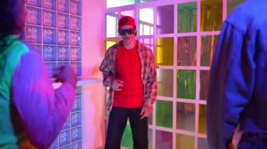 Kafkas dansçısı dans ederken çeşitli arkadaşları gece kulübünde neon ışıkta ayak seslerine bakıyor. Çoklu etnik kökenli hipsterin serbest stil müziğe geçişi ve mutlu bir adamın kameraya bakışıyla. Mutluluk.