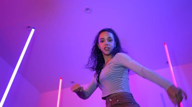 Latin dansçıların kameraya bakıp şehrin pop müziğiyle dans ettiği düşük açılı kamera. Profesyonel çekici hipster, mor veya neon ışıklı hip hop şarkısına geçiyor. Şık bir kumaş. Mutluluk.