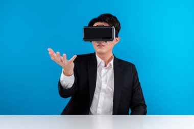Asyalı işadamı VR 'ı kullanarak veri nesnesini havada tutuyor iş dünyasının fütüristik yenilikçi teknolojisini analiz ediyor izole edilmiş mavi telif uzayındaki sanal gerçekliği inceliyor. Entrika.