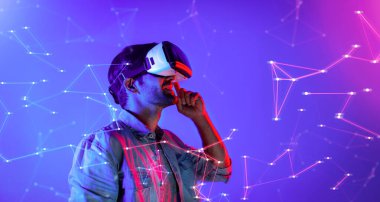 Zeki beyaz adam neon ışıkta dururken VR gözlük takıyor. Teknoloji yeniliklerini kullanarak görsel gerçeklik gözlüğünü kullanarak metaevren ya da görsel dünya programını bağlayabiliyor. Sapma.