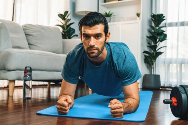 Atletik ve sporcu adam, evde vücut egzersizi yaparken spor ve fiziğe uygun spor yaşam tarzını geliştiriyor. Gaiety evde egzersiz eğitimi.