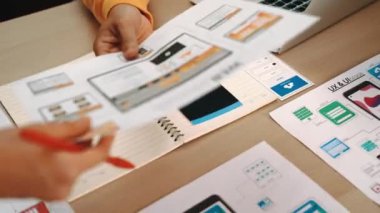 Mobil uygulama için kullanıcı arayüzü prototipini ofis çalışma alanındaki akıllı yöneticiye sunan mükemmel bir şirket çalışanı. UX UI tasarımcısı kağıt üzerinde simge tasarımının işlevini açıklıyor. Sinerjik