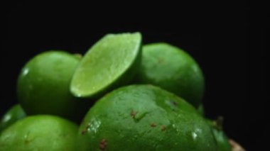 Limon dilimleri titizlikle bir yığın halinde, siyah arkaplana göre dizilmiş. Her bir kireç dilimi çarpıcı detaylar, canlı yeşil rengi ve baştan çıkarıcı dokusu ile yakalanır. Kapatın. Geliştirilebilir.