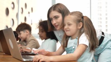 Çok kültürlü bir öğrenci dizüstü bilgisayar kullanarak mühendislik kodları yazarken öğretmen program hakkında açıklama ve öğretim yapıyor. Profesyonel eğitmen BTMM sınıfında programlama sistemini öğrenmeye yardım ediyor. Etkinlik.