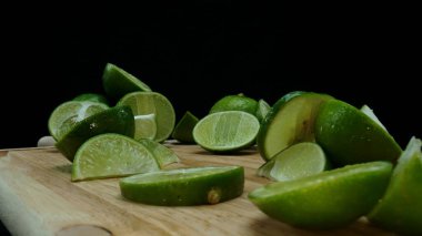 Yakın plan, canlı bir dilim taze kireç kırsal bir ahşap kesme tahtasının üzerinde duruyor. Tazelik ve canlılık yayıyor. Kesme tahtasına konmuş yeşil limon diliminin yarı saydam zarları. Geliştirilebilir.