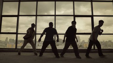 Yetenekli koreograf grubunun gökyüzü dövüşçüsüyle dans ederken çekilmiş siluet fotoğrafı, şehir manzarası arka planı. Genç hipster takımı dans gösterisi. Sepia filtresi. Gölge. Açık hava sporu 2024 hiphop..