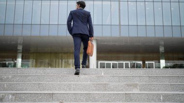 Ofise giderken merdivenlerden çıkan başarılı bir iş adamı bacağı. Proje yöneticisi iş yerini değiştiriyor, yeni bir şey keşfediyor, gelişiyor, terfi ediyor ya da gün ışığına çıkıyor. Ayağa kalkın. Sevinçli..