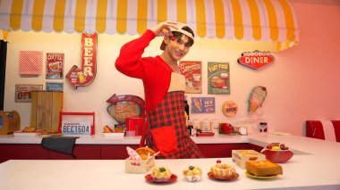 Profesyonel Asyalı restoran işçisi yemek hazırlar ve yemek barının arkasında durur. Kırmızı önlüklü çekici garson kameraya bakarken vişne topluyor. Çılgın dans. Mutluluk.