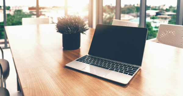 Портативный компьютер с открытой крышкой на столе в офисном рабочем пространстве. uds