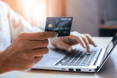 Genç adam, laptop bilgisayar başvurusu ya da web sitesinde online alışveriş yapmak için kredi kartı kullanıyor. E-ticaret ve online alışveriş konsepti. uds