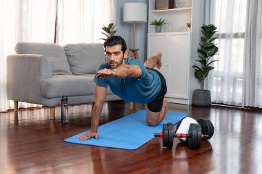 Spor giyimli esnek ve becerikli bir adam evde egzersiz paspası üzerinde meditasyon pozisyonunda yoga yapıyor. Huzurlu ve huzurlu bir yoga yaşam tarzı..