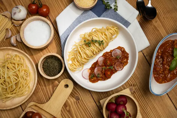 Lezzetli yiyecekler, ev yapımı spagetti, kıymalı domates sosu ve fesleğen fırlatma elementleri, şef masası dekoratif baharatlarla servis ediliyor. Varsayım.