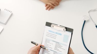 Klinikteki ya da hastane ofisindeki doktor randevusuna katılan hasta, tıbbi tedavi seçeneklerini tartışıyor ve muayene sonuçlarını ya da hastalıkla ilgili tıbbi kayıtları açıklıyor. Ağır çekim. Katı.