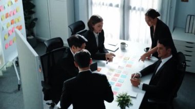 İş adamlarının üst görüşü pazarlama stratejisini açıklıyor ve renkli yapışkan notlar kullanarak fikri seçiyor. Profesyonel pazarlama ekibi toplantı odasında beyin fırtınası yapıyor ve finansal planlar yapıyor. Müdürlük.
