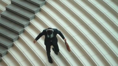 Merdivenlerden inerken kulaklıktan müzik dinleyen profesyonel bir iş adamı. Yetenekli proje yöneticisi kameraya gülümserken merdivenlerden iniyor. Beyaz arka plan. Sevinçli..