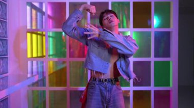 Kameraya bakarken kollarını esneten seksi kıyafetli Asyalı dansçı. Profesyonel sanatçı gece kulübünde renkli neon ışıkları canlı bir şekilde dururken serbest stil dansı yapıyor. Mutluluk.