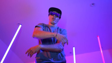 Beyaz dansçının gösterişli gözlükler taktığı ve break dans yaptığı alçak açılı kamera. Çekici adam kendinden emin bir şekilde kameraya bakarken enerjik bir performans ve hareket gösterdi. Mutluluk.