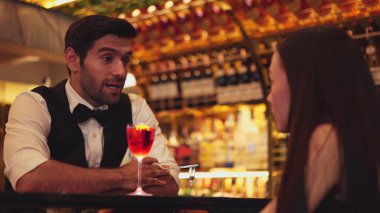 Barmen lüks tezgah barında güzel misafirler için çiçeklerle süslenmiş karışık votka kokteyli servis ediyor. Mükemmel canlı renk sunumu. Atmosfer gece kulübünü ön plana çıkarıyor. Vinosity.