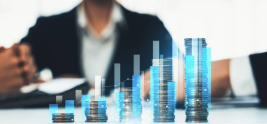 Dijital grafik göstergeli bozuk para yığını iş yatırımını ve ekonomik büyümeyi sembolize ediyor. Finansal hedefe ulaşmak ve kâr sağlamak için finansal planlama yapan bir iş adamı. Kurnaz.