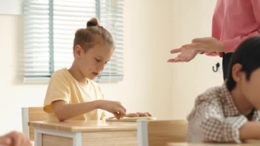 Beyaz bir çocuk ödevlerini yaparken ve açıklama dinlerken güzel bir öğretmen sınavı açıklıyor. Sınıfta not alırken ya da kağıda cevap yazarken öğretmenine bakan sevimli bir çocuk. Pedagoji.