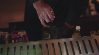 Yakın plan el yapımı barmen. Midori ekşisini limon şurubuyla karıştırıp cam hazırlıyor. Gece kulübünde gece hayatı karışımı sergilenen taze yeşil içeceğe odaklanıyorum. Vinosity.