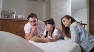 Çocukluk hikayeleri anlatan uyku zamanı, anne ve baba rahat ve rahat yatak odasındaki küçük kızlarına birlikte fantezi kitabı okuyorlar. Modern aile eğlencesi. Titiz