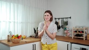 Enerjik beyaz anne kahvaltı için salata pişirirken ve yemek pişirirken elinde kepçeyle şarkı söylüyor. Sağlıklı yemek yapmaya hazırlanırken müziğe yönelen mutlu ev sahibi. Pedagoji.