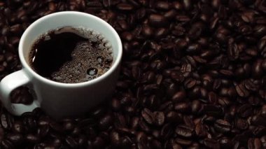 Kahve ya da kahve çekirdekli espresso manzarası. Taze kavrulmuş kahve çekirdeğini yakın çekimde ahşap masanın etrafına bir fincan americano ve aromatik akarsu ve tohum dumanı serpin. Geliştirilebilir.