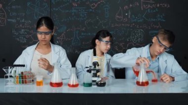 Mesleki çeşitlilik gösteren öğrenci, STEM fen dersinde, kimyasal teoriyle karatahta deneyimi yaşıyor. Genç bir delikanlı biyo-kimyasal çözeltiyi mikroskop ile masada karıştırıyor. Öğretim