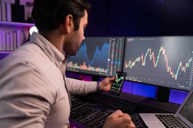 Akıllı tüccar işadamı, karanlık oda gecesinde neon ışıklı ofisteki arama pazarında yüksek kârla ekranda bilgisayar ve bilgisayar üzerinde dinamik borsa yatırımları üzerinde yoğunlaşıyor. Tahmin et..