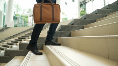 İş adamının bacağına yakın çekim merdivenleri çık. Başarılı bir adam merdivenleri çıkarken yeni bir şey keşfediyor. Seyahat etmeyi, terfi etmeyi, yeni bir iş bulmayı, yeteneğini arttırmayı temsil etti. Sevinçli..