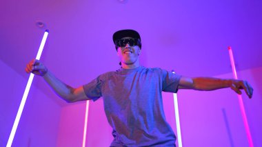 Beyaz dansçının gösterişli gözlükler taktığı ve break dans yaptığı alçak açılı kamera. Çekici adam kendinden emin bir şekilde kameraya bakarken enerjik bir performans ve hareket gösterdi. Mutluluk.