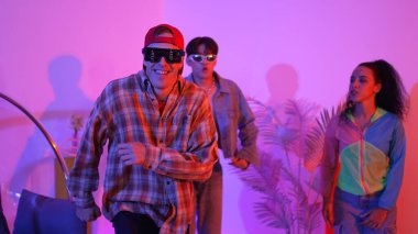 İspanyol hipster renkli kıyafetler giyer ve serbest stil müziğe el sallar. Profesyonel break dansçı neon ışıklarıyla ve modern stüdyo arkadaşlarıyla coşkuyla dans ediyor. Mutluluk.