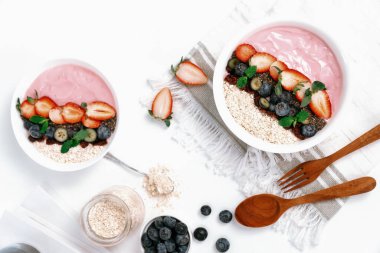 Meyvelerin sunduğu yoğurt malzemelerini çilek, yulaf, kuru üzüm ve nane şekeriyle süslenmiş Chia tohumu ile beyaza boyarız. Pembe arka plan. Sağlıklı süt ürünleri seti. Bireysel.