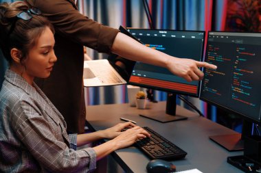 Modern ofisteki neon ışık odasında bilgi ağını gösteren dizüstü bilgisayarla iki ekranda veri çalıştıran akıllı web sitesi geliştirme kodlayıcı sistemini tartışan IT geliştiricilerinin ciddiyeti. İnfobahn.