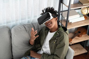 Şaşırmış Afro-Amerikan görünümlü VR oturma odasındaki fantastik üç boyutlu çizgi film teknolojisi sanal gerçekliğinde yeni dünya yolculuğunu izlemekten zevk alıyor. Entrika.
