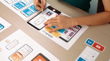 Mobil uygulama için kullanıcı arayüzü prototipi ya da masadaki program modeliyle birlikte web sitesi planlaması yapan bir şirket çalışanı. UX UI tasarımcısı kullanıcı dostu arayüz planını dikkate alır. Sinerjik